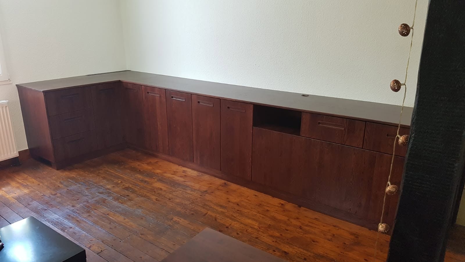 Lange maßgefertigte Einbauzeile aus dunklem Holz entlang einer Wand