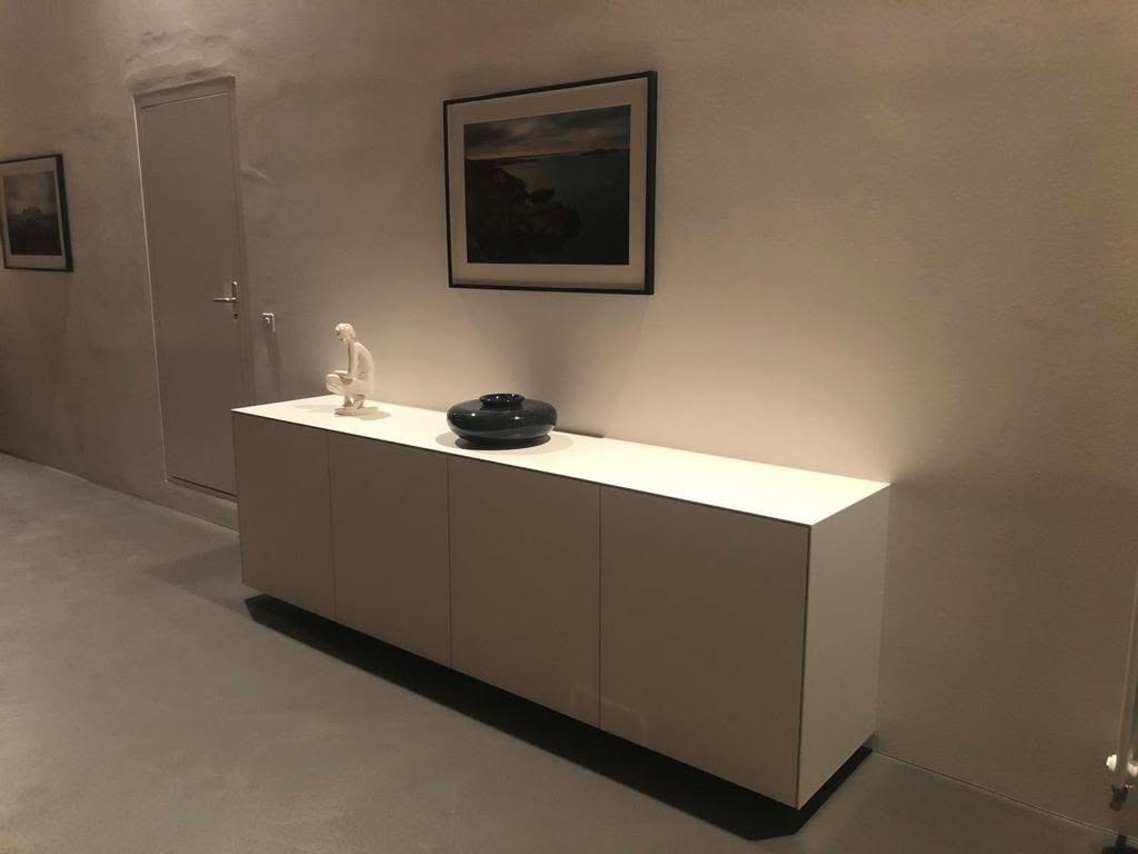 Schwebendes weißes Sideboard in einer Nische mit zurückgesetztem dunklem Sockel
